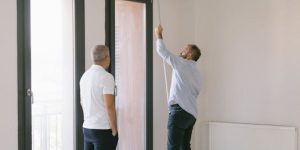 Two men measuring window dimensions in a bright Istanbul apartment.